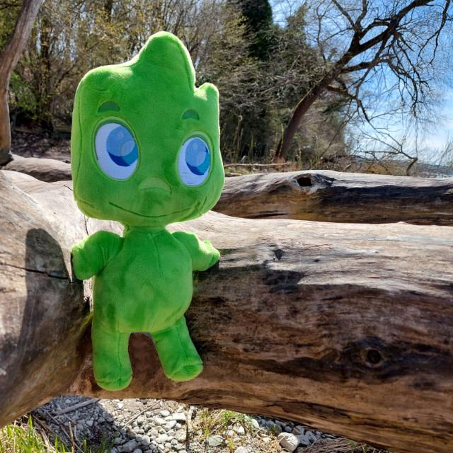 Feel Free Maskottchen aus Plüsch auf Baumstamm